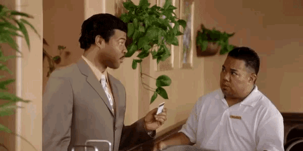 a man in a suit and tie is talking to another man