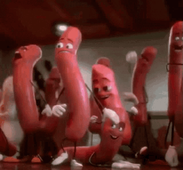 a group of red sausages with faces are dancing together .