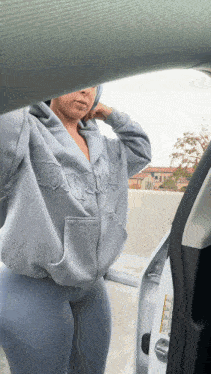a woman wearing a grey hoodie with the word bitch embroidered on it
