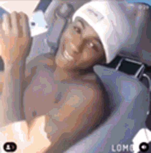 a shirtless man wearing a white hat is sitting in a car .