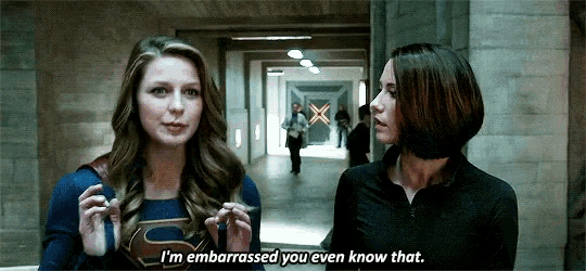 two women are standing next to each other in a hallway and one of them is wearing a superhero costume .