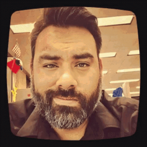 a man with a beard looks at the camera with a sad look on his face