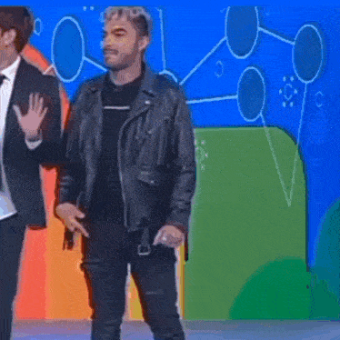 a man in a leather jacket is dancing in front of a colorful wall .