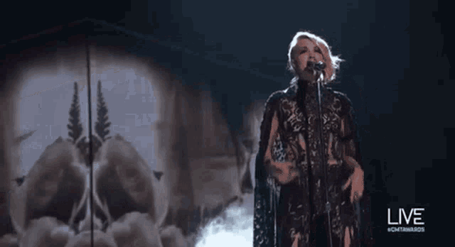 a woman is singing into a microphone on stage .