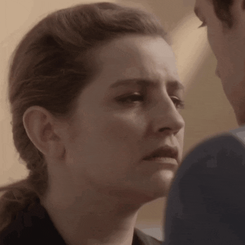 a close up of a woman 's face with a man 's face in the background .