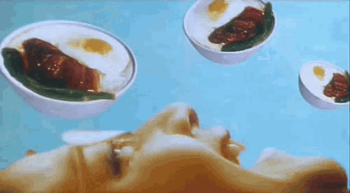 a close up of a person 's face with bowls of food floating in the air .