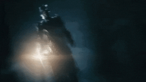 a silhouette of a person in a dark room with a light shining through the smoke .