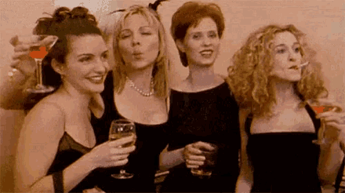a group of women standing next to each other holding wine glasses .