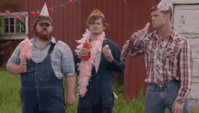 three men wearing party hats and overalls are standing in front of a red building