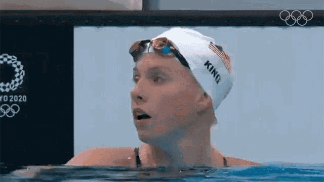 a woman wearing a swim cap and goggles is swimming in the water .
