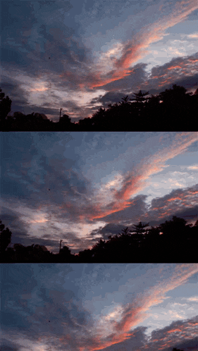 a sunset with trees in the foreground and a few clouds in the background