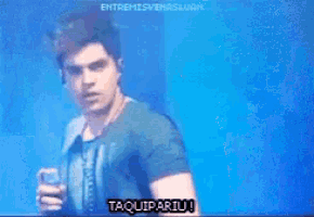 a man in a blue shirt is holding a can and says taquipariu !