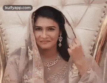 a woman in a veil is sitting in a chair and smiling .