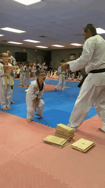 a group of kids are practicing martial arts with a man in a white uniform