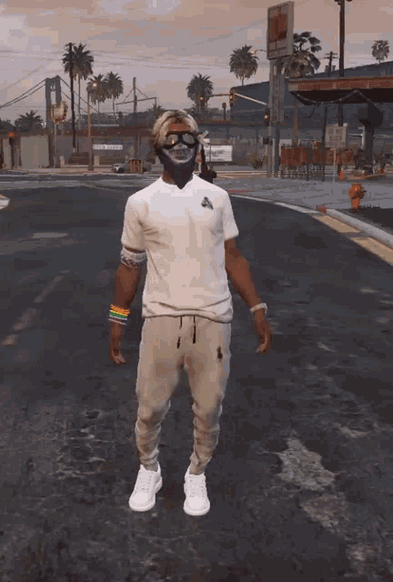 a man wearing a white t-shirt and white sweatpants is standing on a street