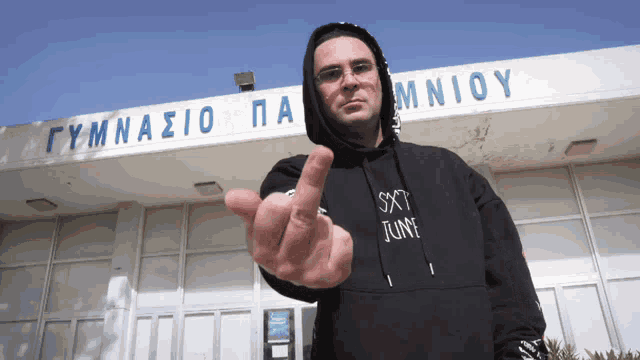 a man giving the middle finger in front of a gymnasio