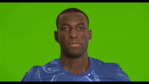 a man in a blue shirt is smiling against a green screen