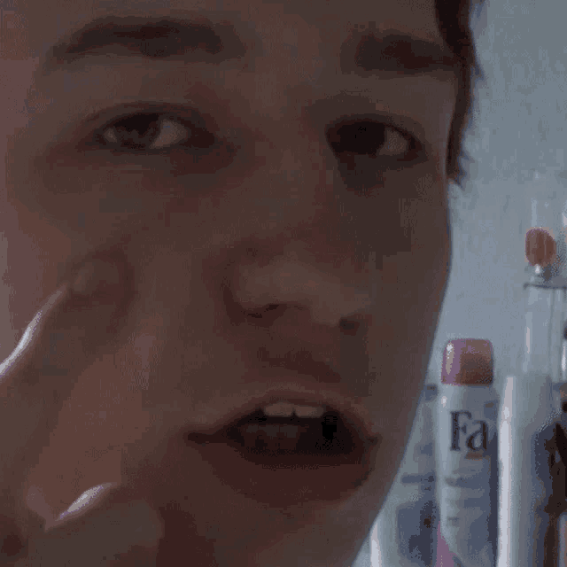 a close up of a person 's face with a bottle of fa lotion in the background