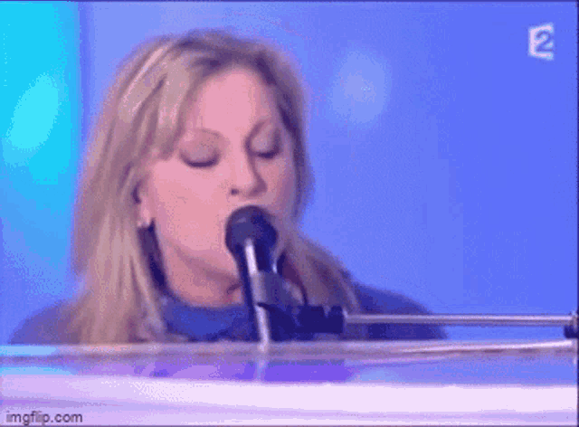 a woman singing into a microphone while sitting at a piano
