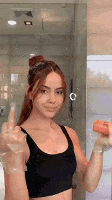 a woman in a black tank top is giving the middle finger in front of a mirror