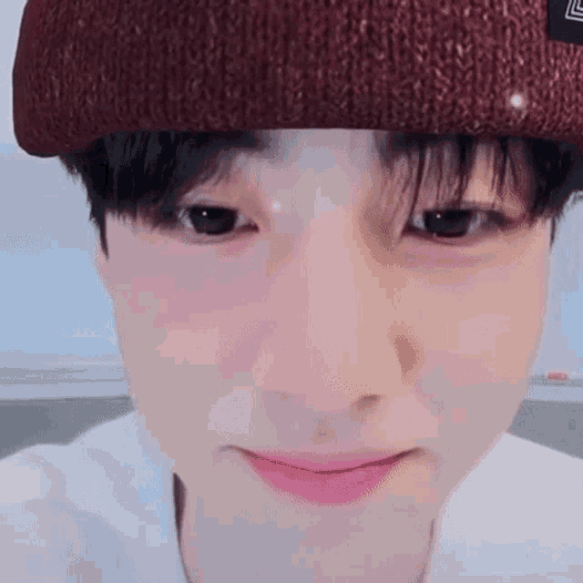 a close up of a young man wearing a knitted hat and a white shirt .