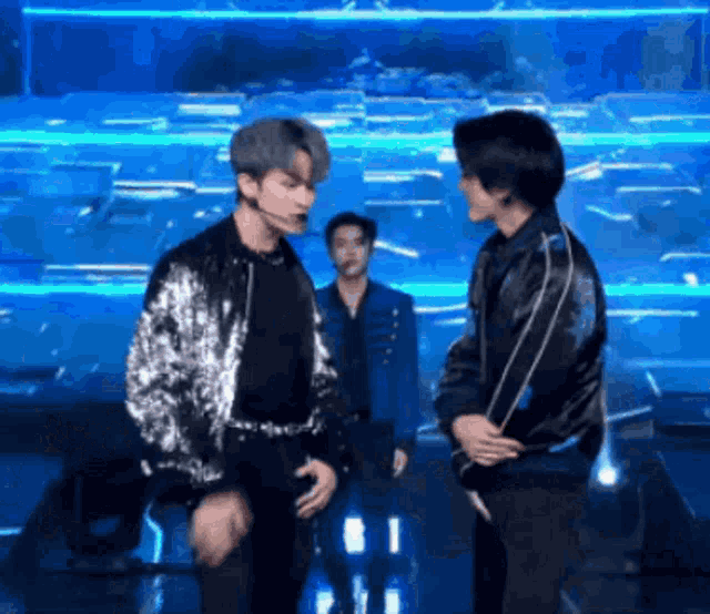 two men are standing next to each other on a stage in front of a blue backdrop .