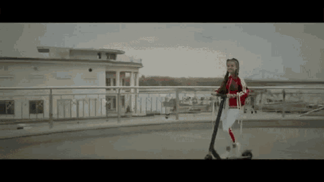 a girl is riding a scooter on a bridge .