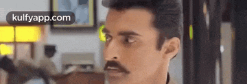 a man with a mustache is standing in a room .