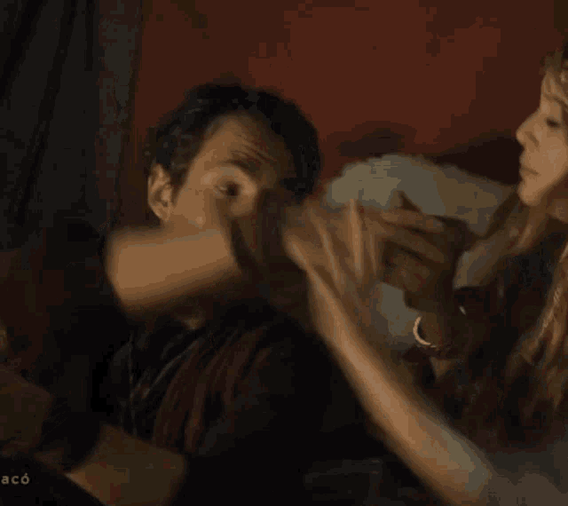 a man with a beard is being kissed by a woman with the word aco on the bottom right