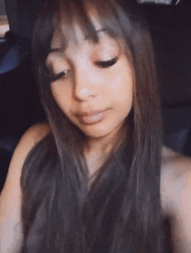 a woman with long hair and bangs is taking a selfie in a car