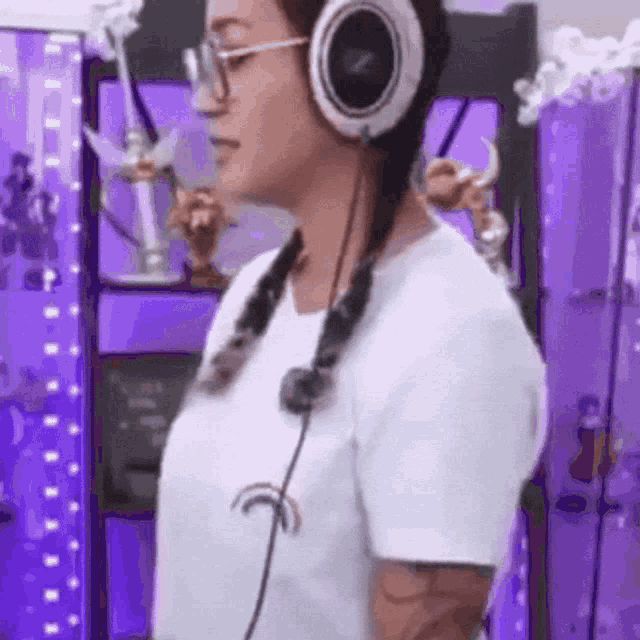 a woman wearing headphones and glasses is standing in front of a purple wall