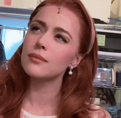 a woman with red hair wearing pearl earrings and a pink headband