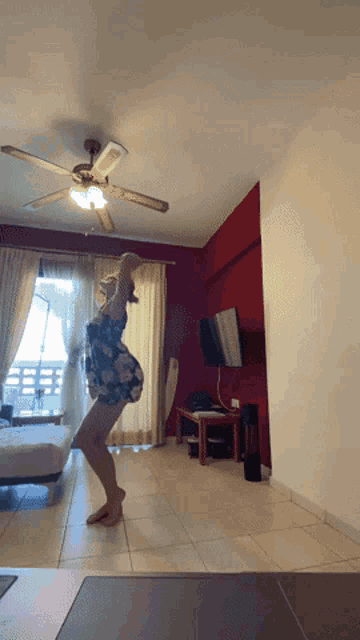 a woman in a floral dress is dancing in a living room