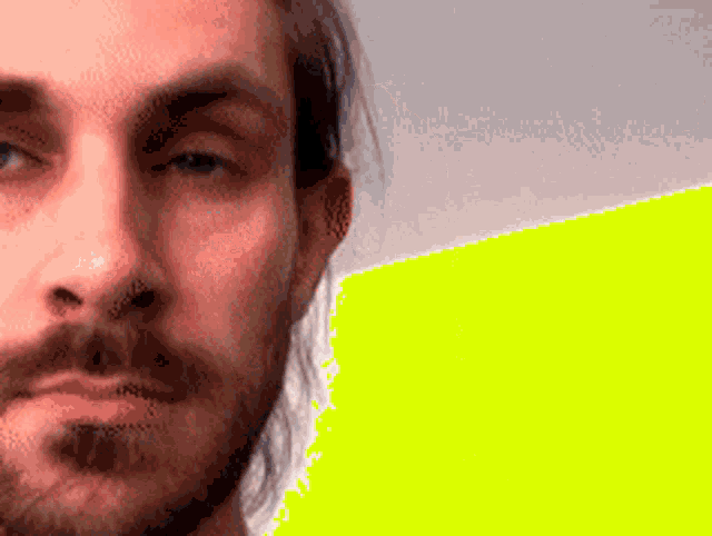 a man with long hair and a beard is looking at the camera