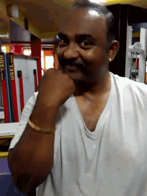 a man in a white shirt has his hand on his chin in front of a shelf that says usel