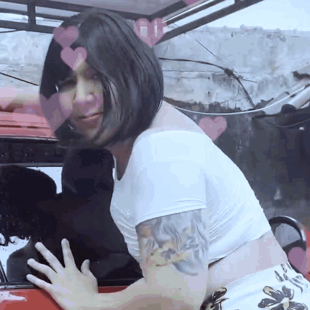 a woman with a tattoo on her arm touches a red car