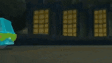 a scooby doo van is driving down the street in front of a building at night .