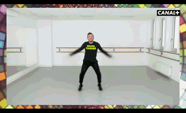 a man in a black shirt that says menu chore stands in a dance studio