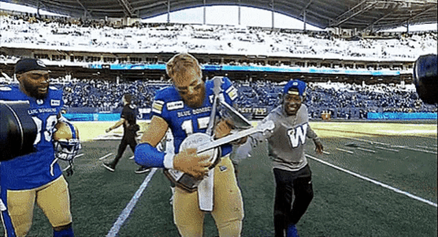 a football player is holding a trophy on the field .