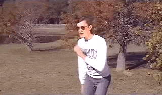 a man is running in a park wearing sunglasses and a white shirt .