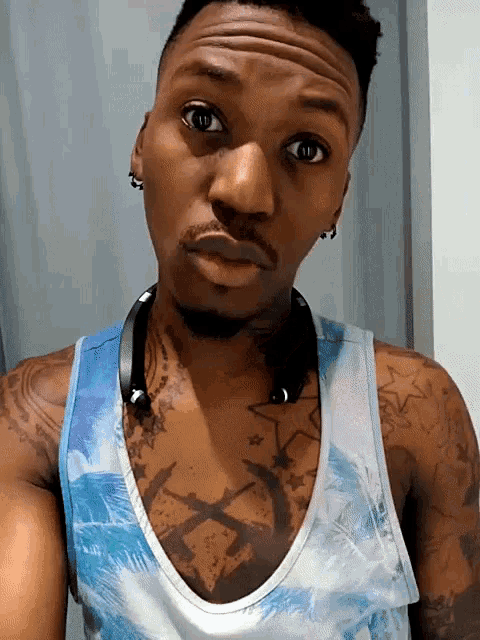 a man wearing a blue and white tank top has tattoos on his chest and arms