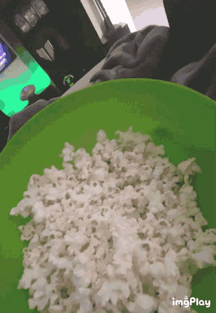 a green bowl filled with popcorn has the word imgplay on the bottom right