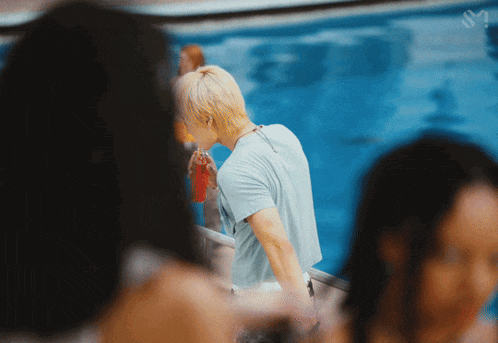 a man in a blue shirt stands in front of a pool