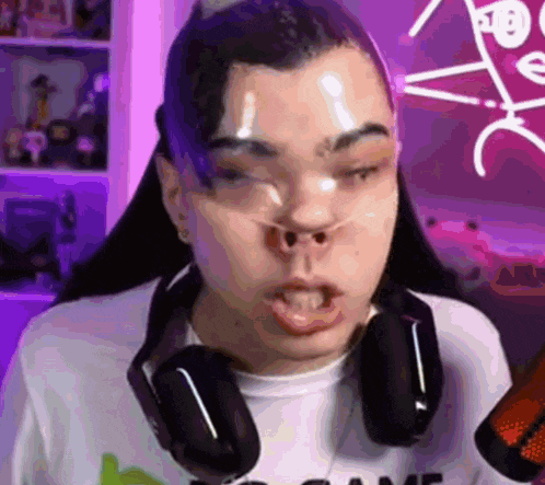 a man wearing headphones and a t-shirt with the word game on it is making a funny face .