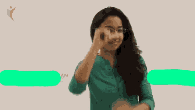a woman wearing glasses and a green shirt points her finger up