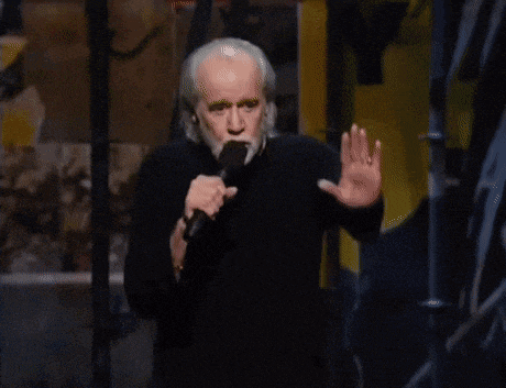 an older man with a beard is holding a microphone and making a stop sign
