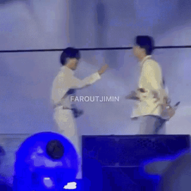 a couple of men are standing next to each other on a stage and shaking hands .