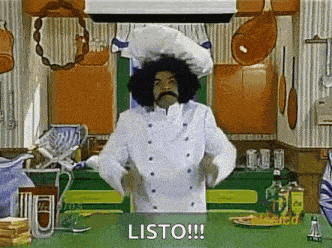 a chef with an afro and mustache is standing in a kitchen .