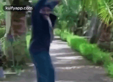 a man is walking down a path in a park with his arms in the air .