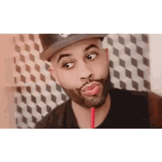 a man with a beard is drinking through a straw and making a face .